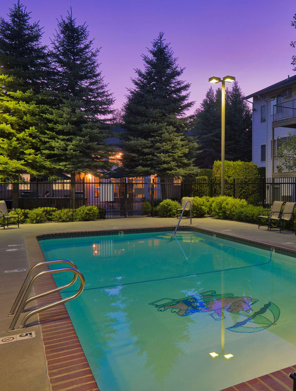 a swimming pool at night with a purple sky