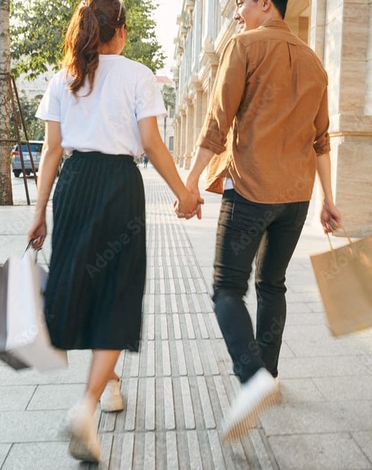 a young couple walking down the street with shopping bags