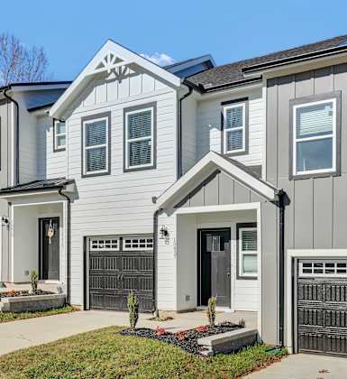 A modern two-story house with a black car parked in front.