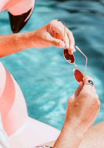 Woman Sitting on Pool Float Holding Sunglasses
