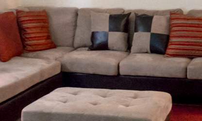 A black leather couch sits in a living room with a coffee table in front of it.