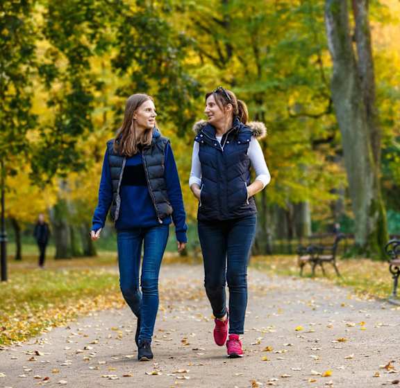 two women walking down a path in a park