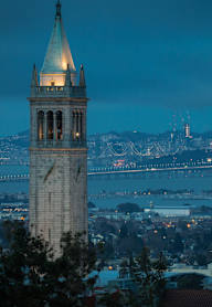 A clock tower stands tall with a cityscape in the background.