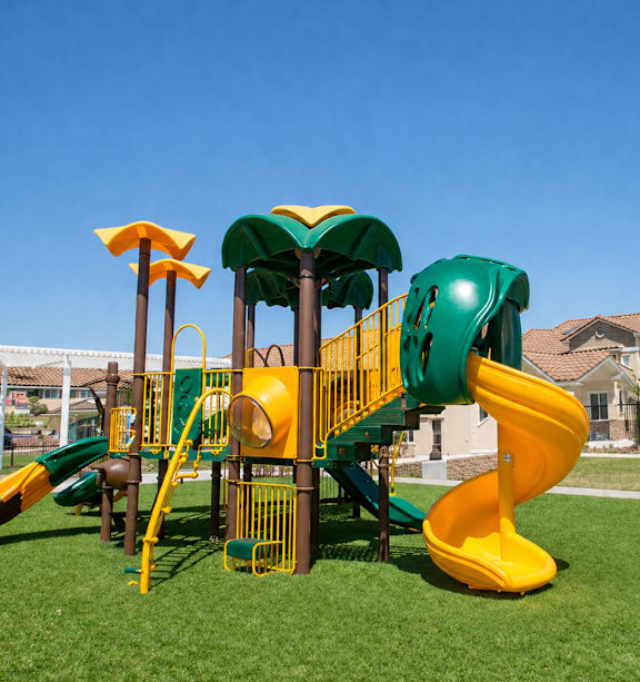 A playground with a yellow and green slide.