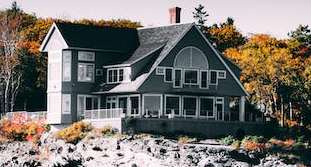 A house is built on a rocky outcrop by the water.