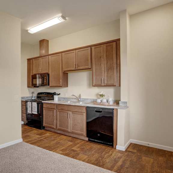 A kitchen with wooden cabinets and a sink and a stove at 600 Riverside. 