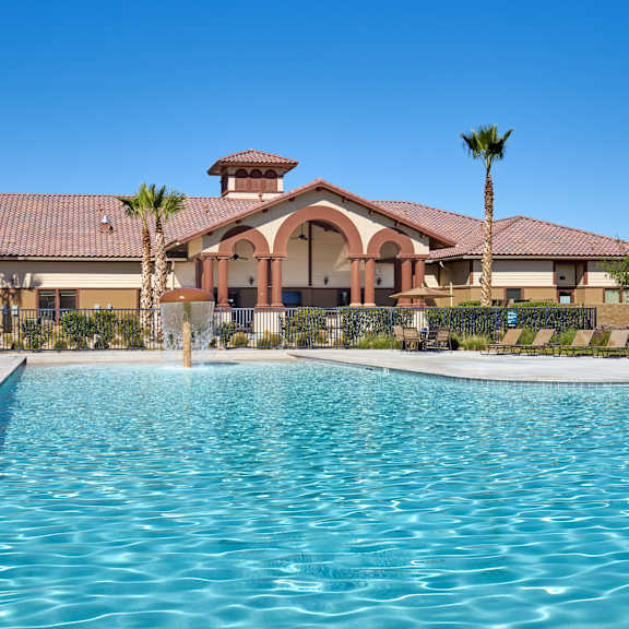 A pool in front of a building with palm trees.