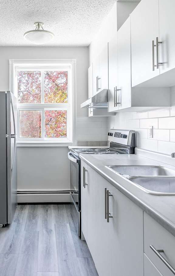 A modern kitchen with white cabinets and stainless steel appliances.