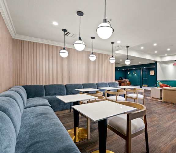 A modern dining area with grey couches and wooden tables at 505 Collection in Atlanta, GA