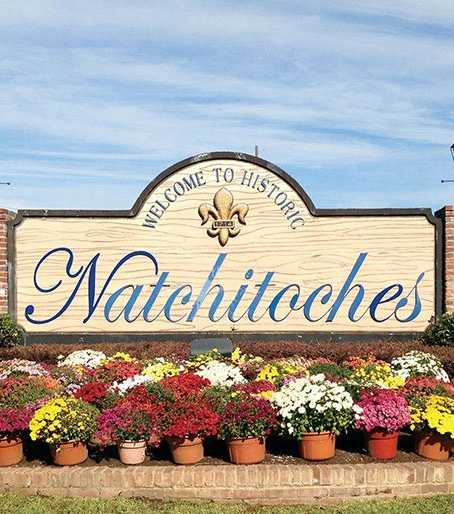 A sign that says Natchitoches surrounded by flowers.