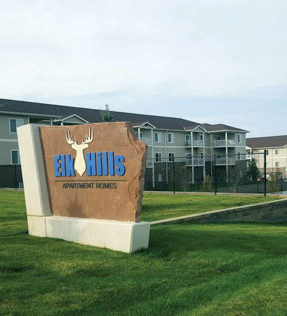 A sign for Eco Hills Apartment Homes sits in front of apartment buildings.