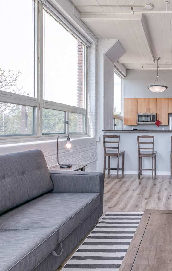 A living room with a grey sofa and a striped rug.