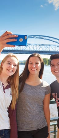 three people taking a picture of themselves with a bridge in the background