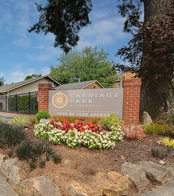 The entrance to Carriage Park is marked by a sign and a flower bed.