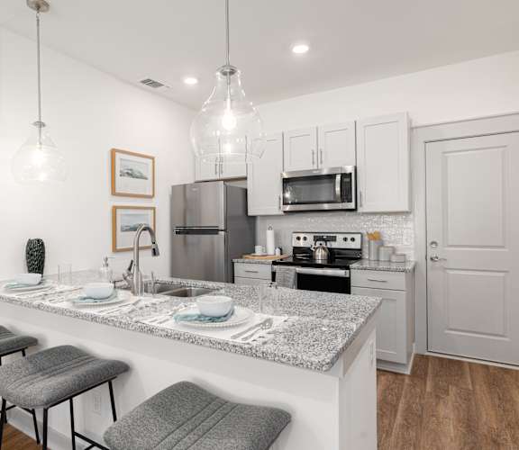 A kitchen with a granite countertop and stools.