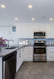 a kitchen with white cabinets and black appliances