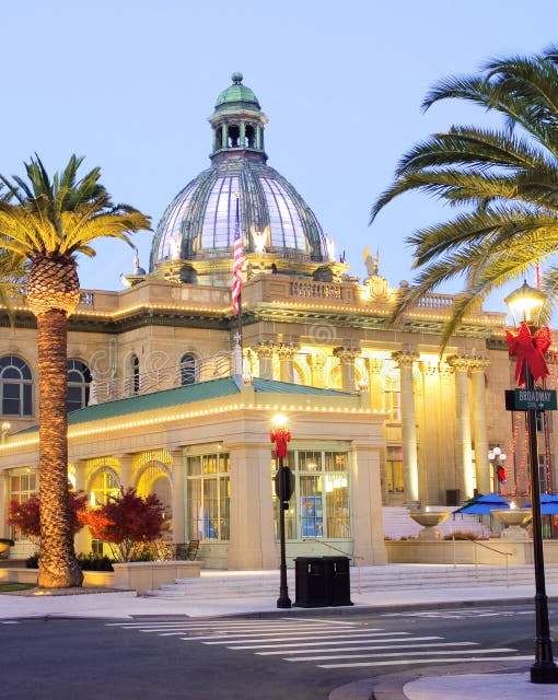 A large building with a dome and palm trees in front.