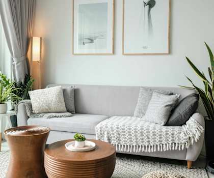 A living room with a grey couch, a wooden table, and two framed pictures on the wall.