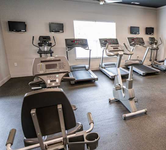 A gym with a variety of equipment including treadmills, weights, and exercise machines.