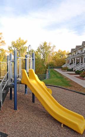 A playground with a yellow slide and a metal structure.