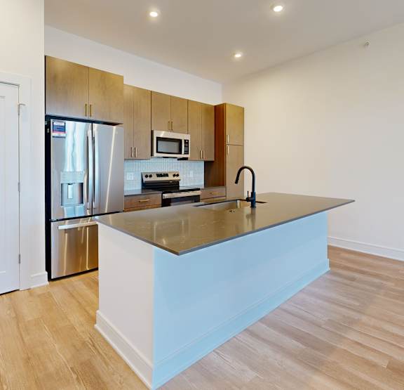 A kitchen with a blue island and wooden floors.