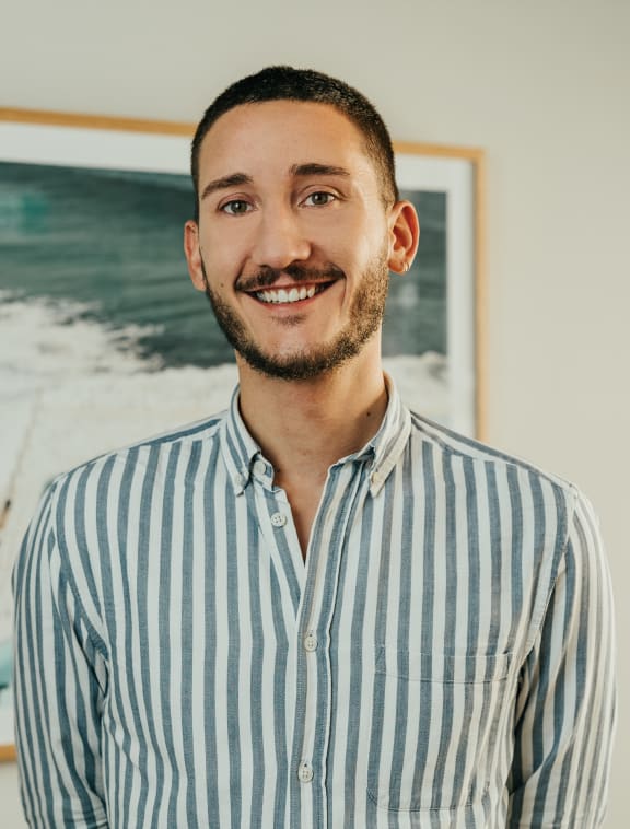 a man in a striped shirt standing in front of a painting