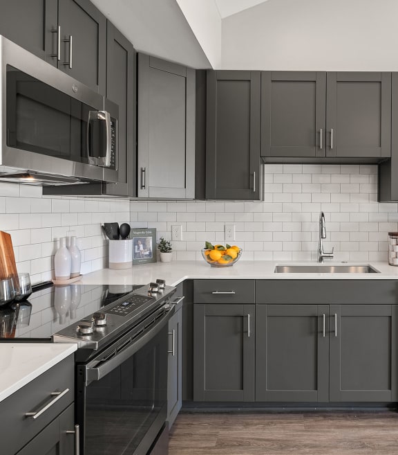 a kitchen with black cabinets and white counters and a sink