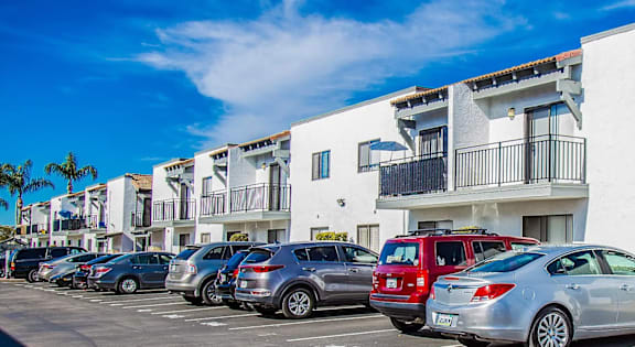 a parking lot with cars parked in front of apartments