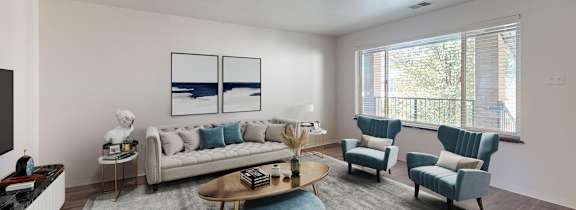 A modern living room with a white sofa, a grey armchair, a coffee table, and a television.