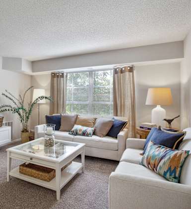A living room with a white couch, a coffee table, and a wooden wall panel.