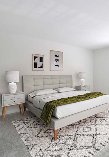 A bedroom with a bed, a chair, and a plant.
