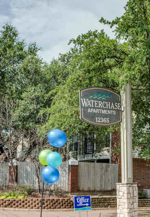 A sign for Waterchase Apartments stands in front of a building.