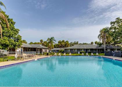 a large swimming pool with buildings in the background and trees