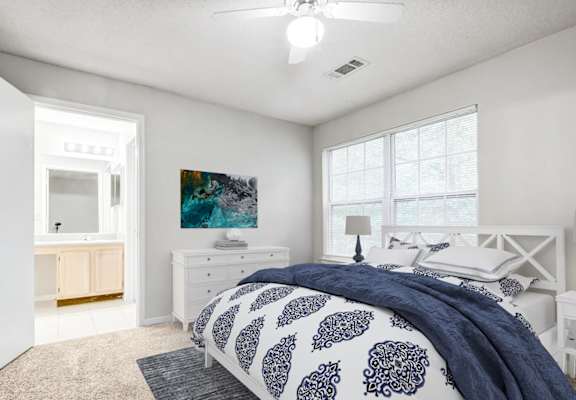 a master bedroom with a large bed and a bathroom in the background