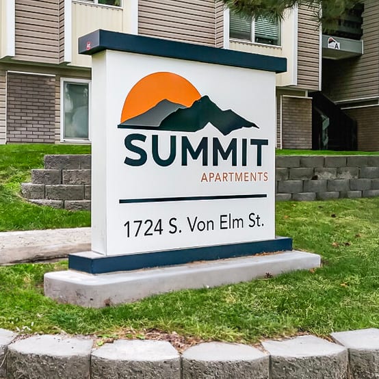 summit apartments exterior sign surrounded by green grass