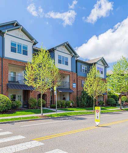 A street view of a residential area with a crosswalk and a pedestrian sign.