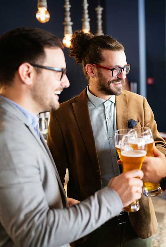 Two men toasting with beer glasses in a bar.at Montage, Tigard, OR