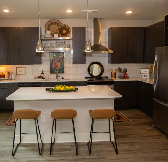 a kitchen with dark wood cabinets and a white island with three stools