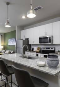 an open kitchen and living room with a granite counter top