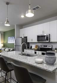 an open kitchen and living room with a granite counter top