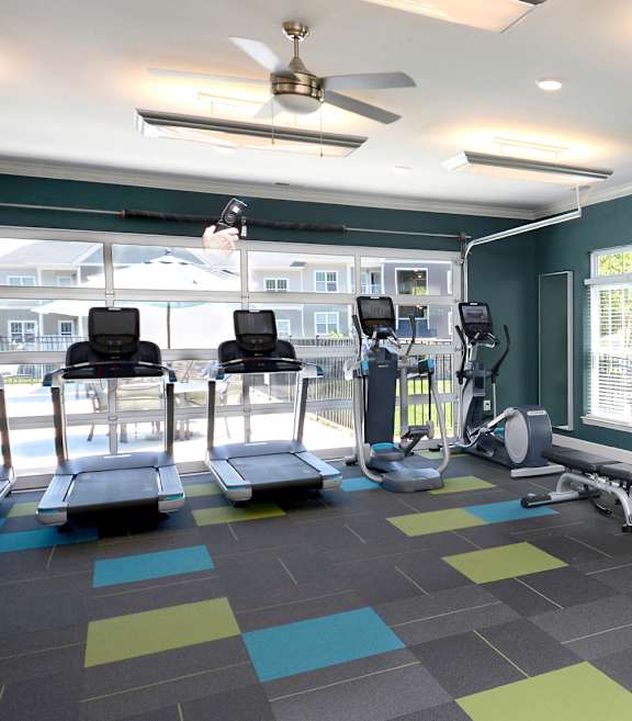 A gym with a variety of equipment including treadmills, stationary bikes, and weight machines.