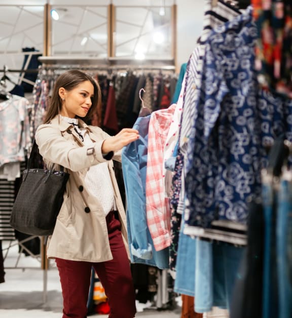 Woman in Clothing Store Holding Up Jacket and Browsing 
