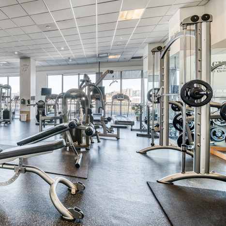 A gym with a variety of equipment including treadmills, weights, and exercise machines.
