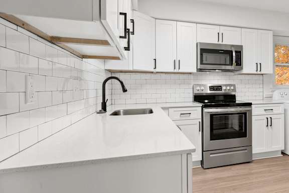 an empty kitchen with white cabinets and a white counter top