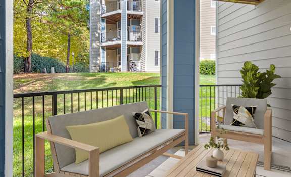 A balcony with a couch, chair, and table with a plant on it.