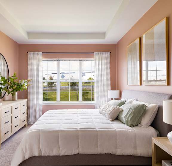 A bedroom with a large bed, a dresser, and a window with curtains.