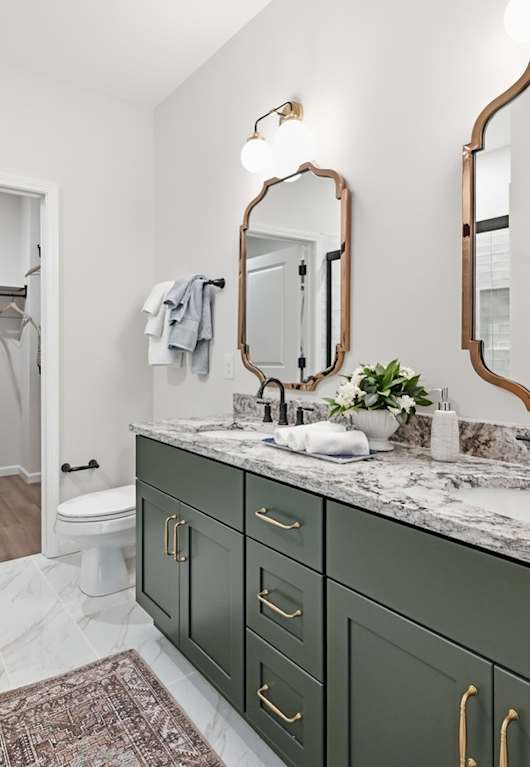 A bathroom with green cabinets and a marble countertop.