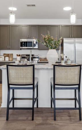 a kitchen with a large island with two chairs and a refrigerator