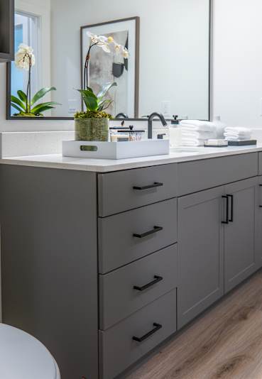A bathroom with a large mirror, a sink, and a towel hanging on the door.