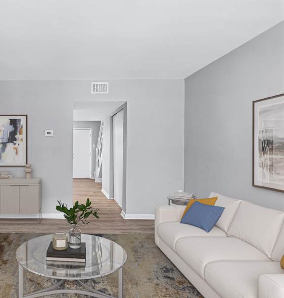 A living room with a white couch and a glass coffee table.